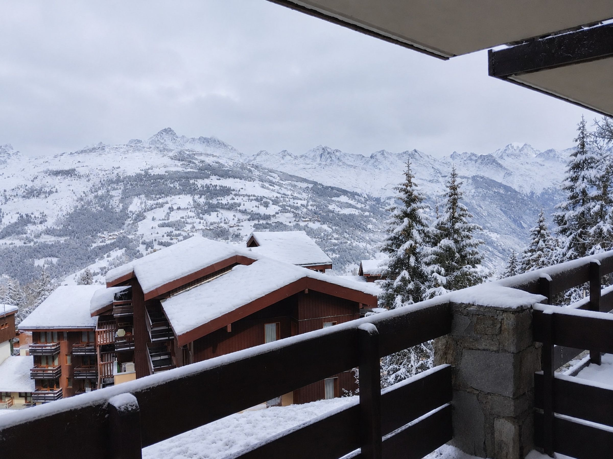 A mountain lodge with a wooden staircase and a view of snow-covered peaks.