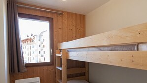 Ein kleiner, hölzerner Raum mit einem Etagenbett und einem Fenster mit Blick auf ein Gebäude.