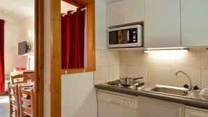 Une cuisine compacte équipée d’un four à micro-ondes, d’une cuisinière, d’un évier et de chaises en bois.