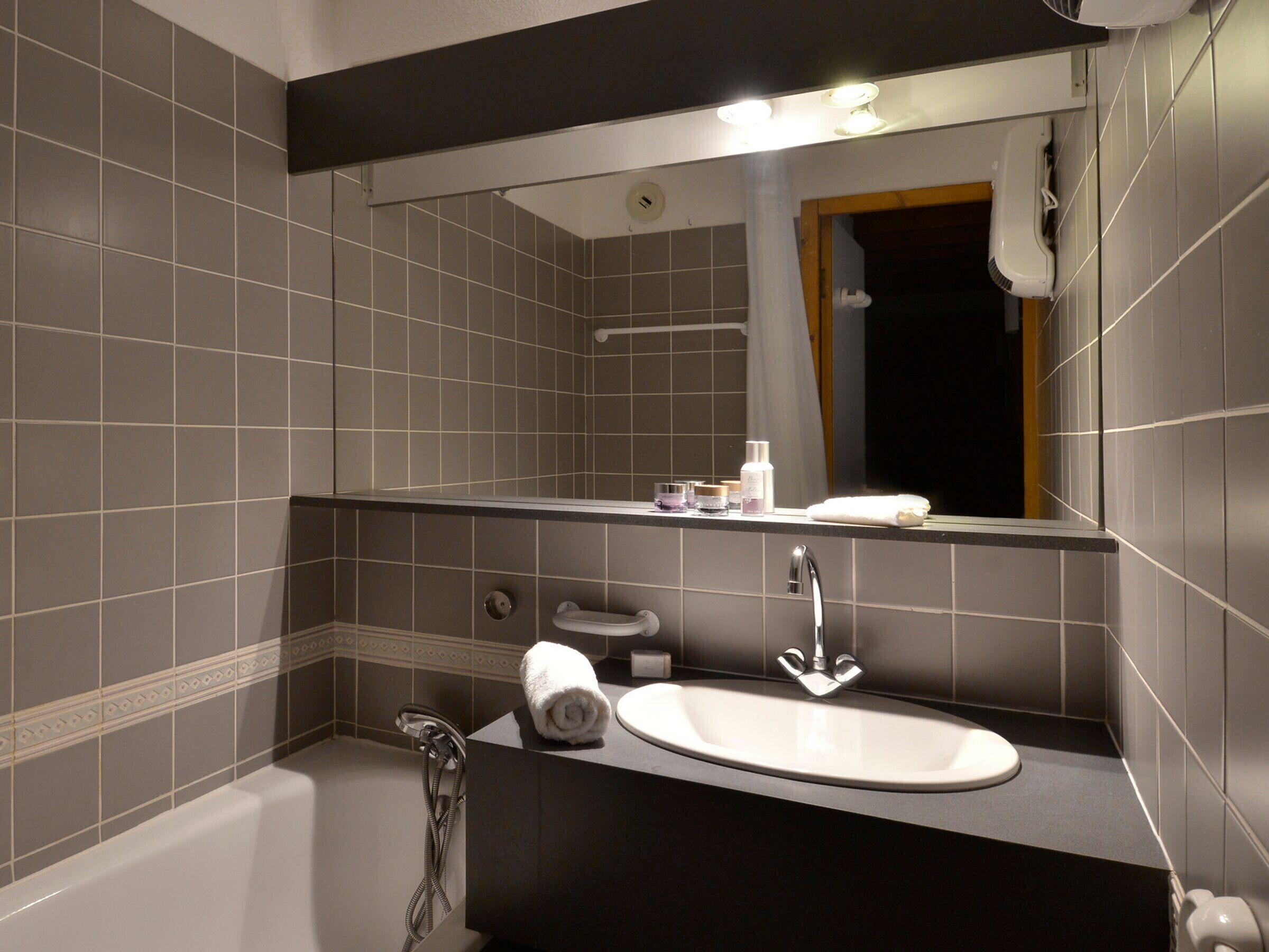 A modern bathroom with a bathtub, a sink, and a large mirror.
