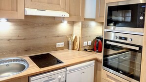 Una cocina moderna con armarios de madera, horno empotrado, lavavajillas y estufa.