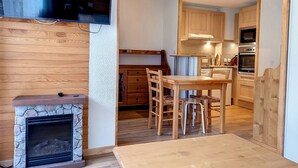 Una cocina moderna con armarios de madera, una mesa de comedor y un televisor integrado.