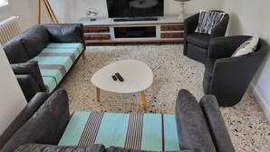 Ein modernes Wohnzimmer mit einer Sofagarnitur, einem Couchtisch und einem Fernseher auf einem Holzboden.