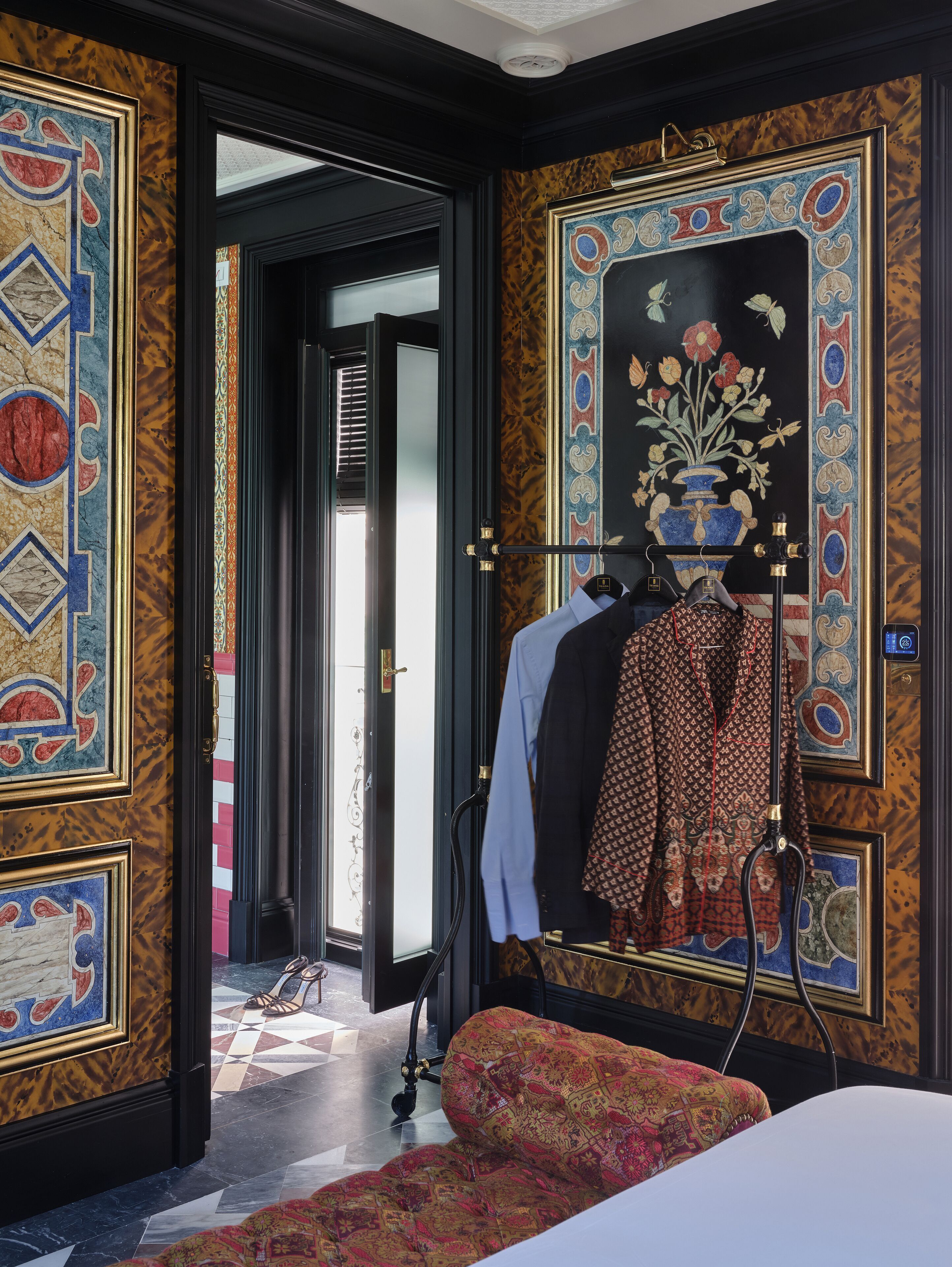 A room with a patterned wall, a mannequin with clothes, and a door leading to another room.