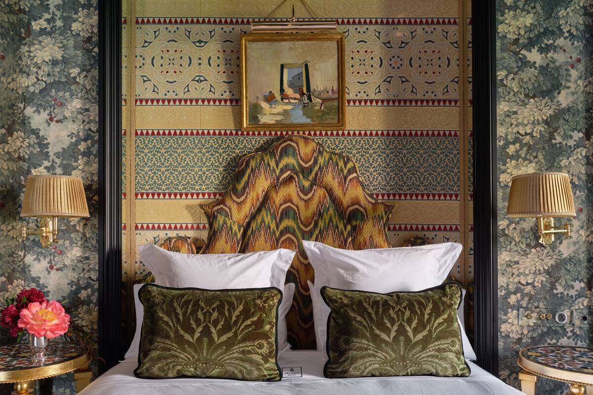 Une chambre d’hôtel avec un grand lit, deux oreillers, un tableau au mur et deux appliques murales.