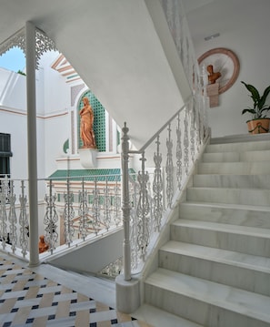 Uma escadaria com grades brancas ornamentadas e acabamento em mármore.