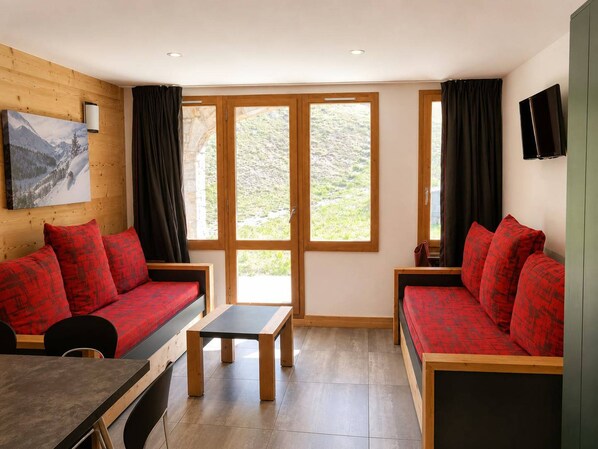 A room with two red sofas, a wooden table, and a painting on the wall.
