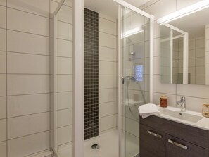 A modern bathroom with a glass-enclosed shower, a white tiled wall, a dark wood vanity, and a large mirror. - Renovated studio near slopes with wifi, pets allowed (Briançon)