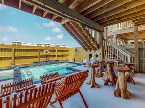 A wooden deck with a pool, outdoor seating, and a staircase.