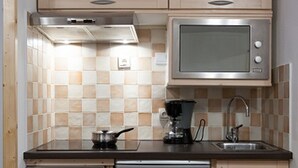 A compact kitchen with a microwave, coffee maker, sink, and dishwasher.