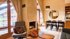 Ein gemütliches Wohnzimmer mit Kamin, Essbereich und großen Fenstern mit Blick ins Freie.