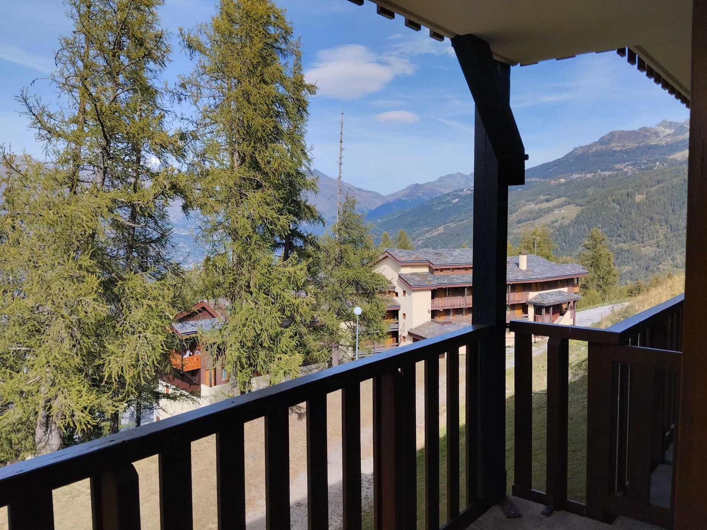 Un balcon offrant une vue sur un paysage montagneux, avec notamment un bâtiment doté de plusieurs balcons.