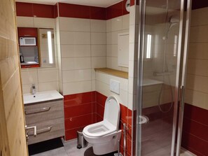 Un baño con inodoro, lavabo y zona de ducha.