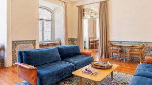 Amplia sala de estar con sofá azul, mesa de centro de madera y un comedor con sillas y una mesa.