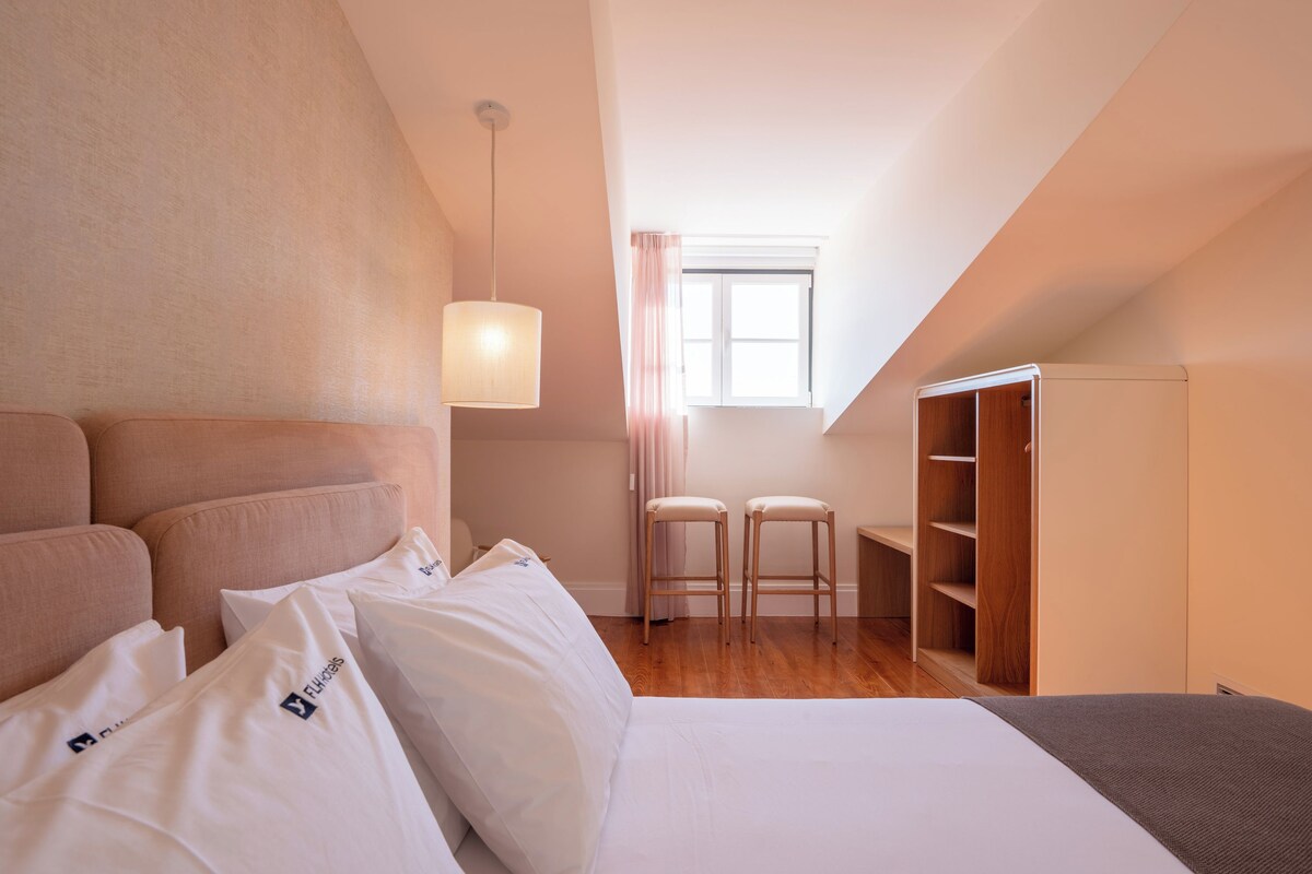 Une chambre à coucher comprenant un lit, une armoire, une fenêtre et un luminaire suspendu.