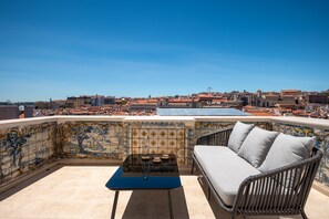 Une terrasse sur le toit, avec un canapé en osier, une petite table et un mur recouvert de carreaux formant une mosaïque.