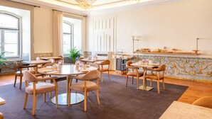 Un comedor con mesas y sillas redondas, una araña y un salpicadero de azulejos.