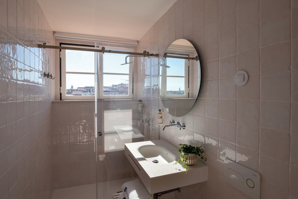 Un baño moderno con un ventanal grande, una bañera, un lavabo y un espejo.