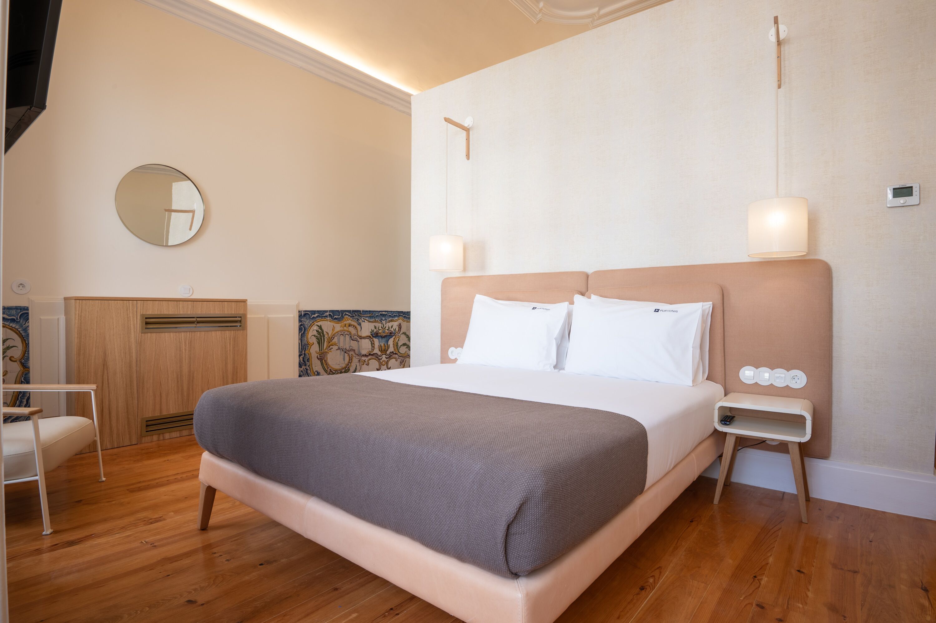 Ein ordentlich eingerichtetes Schlafzimmer mit einem großen Bett, Nachttischen, einem Spiegel und einer Wandleuchte.