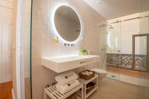 Une salle de bain moderne avec un grand miroir, un lavabo blanc et une cabine de douche en verre.