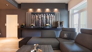 A modern living room with a sectional sofa, a coffee table, and a large abstract painting on the wall. - Maison Privee - Luxurious 2/Bed Apt on Palm Jumeirah (Dubai)