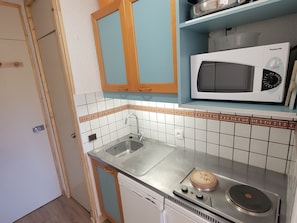 A compact kitchen with a sink, a microwave, and a stove.