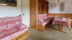 Un cuarto acogedor con un conjunto de sofá de madera, una mesa de comedor con mantel a cuadros y un banco de madera.