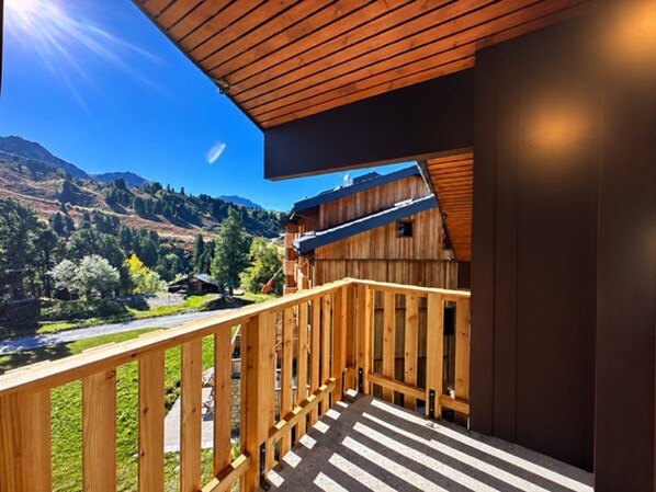 A wooden balcony with a view of a mountainous landscape.