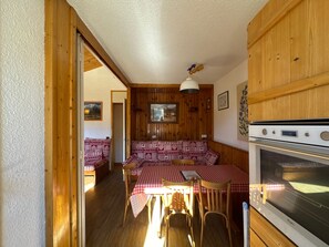 A cozy room with a wooden ceiling, a dining table with a checkered tablecloth, and a built-in oven.