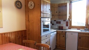 Una cocina funcional con armarios de madera, horno empotrado, lavavajillas y una ventana sobre el fregadero.