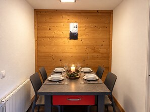 A dining area with a wooden wall, a table set for four, and a red drawer below.