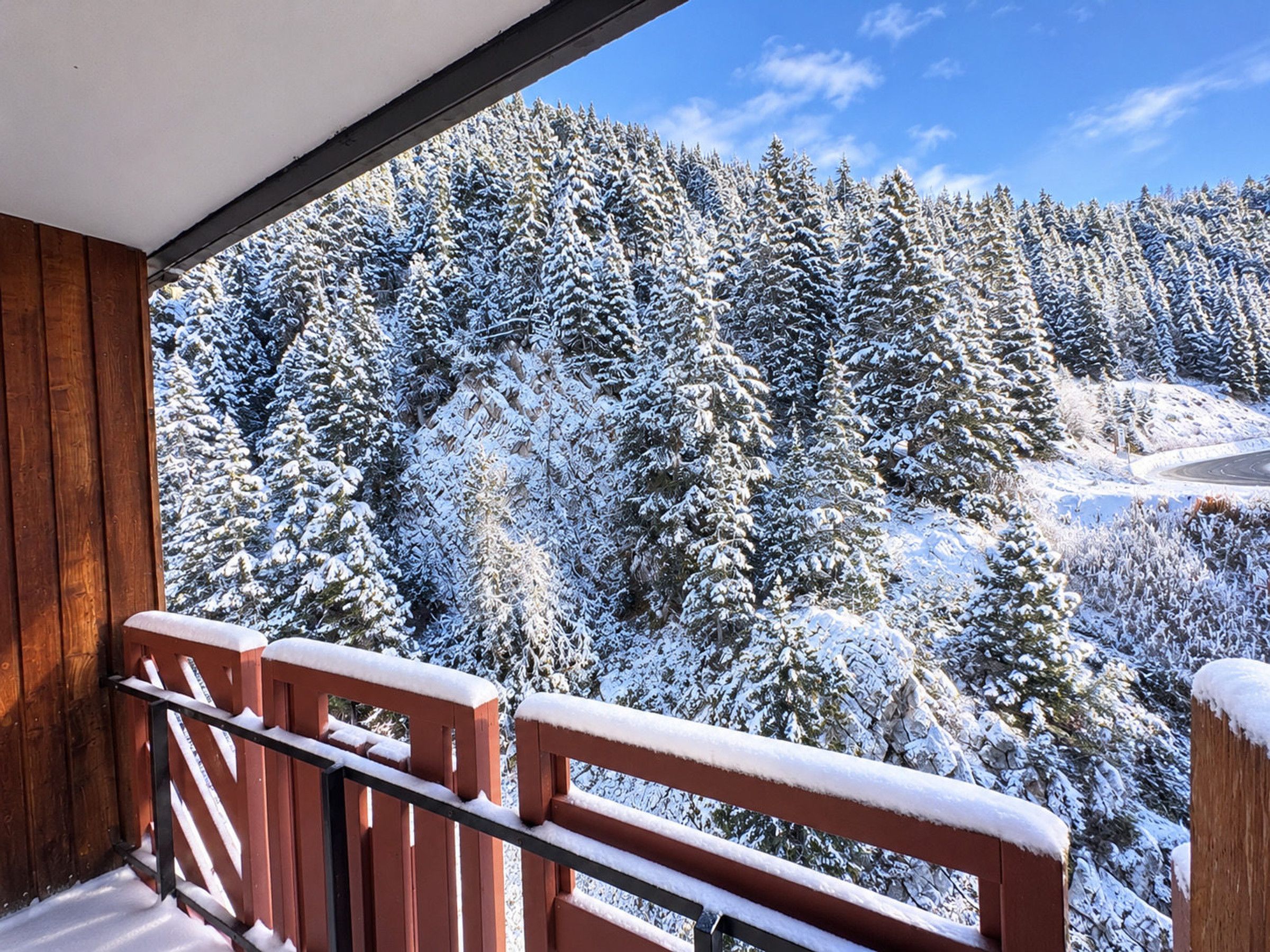 A balcony with a view of a snow-covered forest.