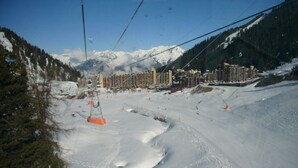 A ski resort with a ski lift, snow-covered slopes, and buildings in the background.
