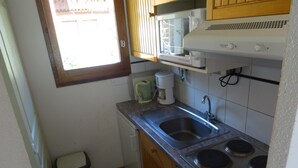 A compact kitchen with a sink, stove, and microwave.