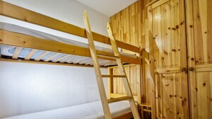 A bunk bed with a wooden ladder, a white mattress, and a wooden wardrobe with multiple doors. - Cozy studio in Flaine, south balcony, near slopes (Flaine)