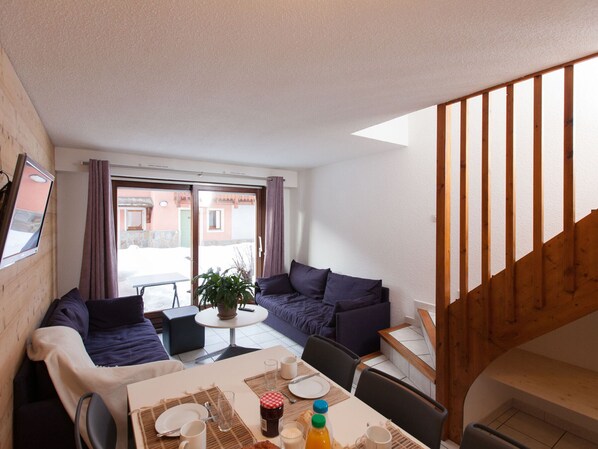 Una sala acogedora con sofá, mesa de comedor y una escalera.