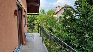 Ein Balkon mit Metallgeländer, einer Bank und einer Tür.