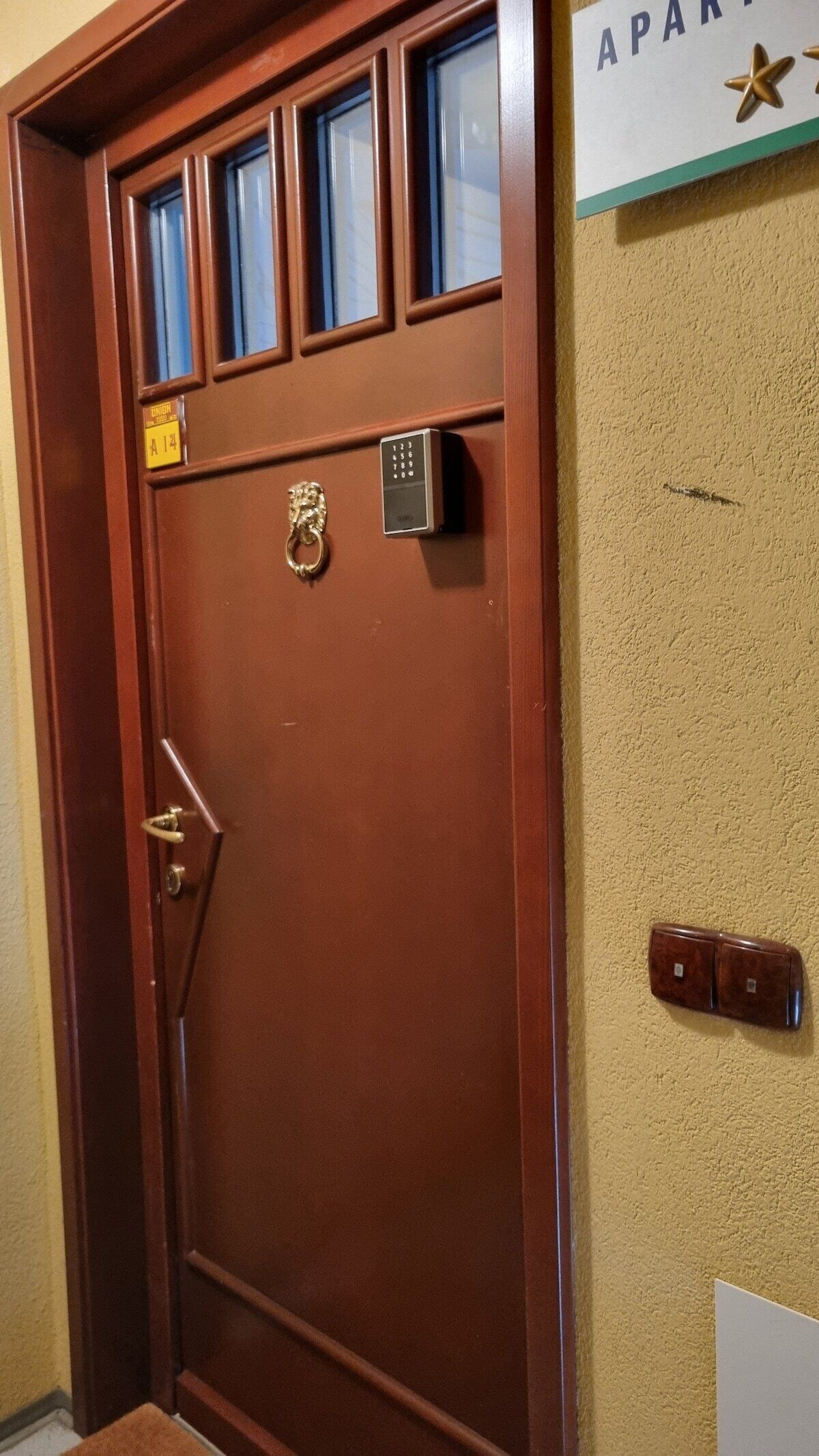 A brown door with a keypad lock, a keyhole, and a small plaque.
