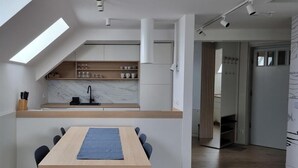 Eine moderne Küche mit Oberlichter, einer Holzausziehtischplatte und einem Essbereich mit Tisch und Stühlen.