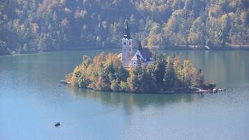 A small island with a church and a tower surrounded by a forested lake.