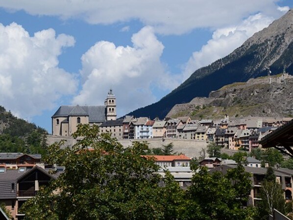 A town with a prominent church and a mountain backdrop. - Studio at the foot of the slopes with Wifi and pets allowed (Briançon)