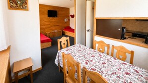 A compact room with a dining table, two single beds, a TV, and a kitchenette. - Comfortable 2-room apartment, direct slope access, sleeps 6 (Belle Plagne)