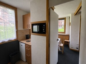 A compact kitchen with a microwave, a coffee maker, and a small refrigerator.