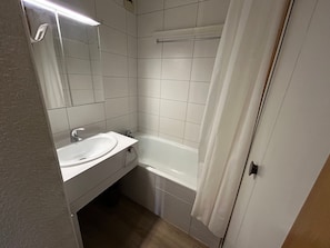 Un baño con lavamanos blanco, espejo y bañera.