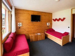 Una habitación con dos camas de madera, un televisor y una pared de madera.