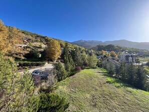 Un quartier résidentiel situé sur une colline, avec des maisons, un ciel dégagé et des montagnes en arrière-plan.