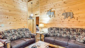 Ein gemütliches Blockhauss-Interieur mit zwei Ledersofas, einem Holztisch und einer Lampe.