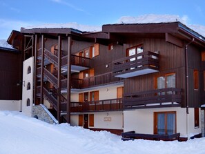 Un hôtel à plusieurs étages, doté de balcons en bois et d’un escalier en pierre.