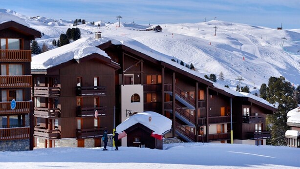 A wooden lodge with multiple balconies and a ski lift in the background. - Spacious apartment 5 guests · Ski-in/ski-out · Balcony with views (Belle Plagne)