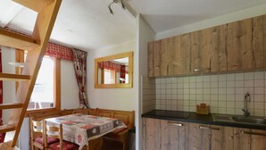 A compact kitchen with wooden cabinets, a black countertop, and a tiled backsplash. - Spacious apartment 5 guests · Ski-in/ski-out · Balcony with views (Belle Plagne)